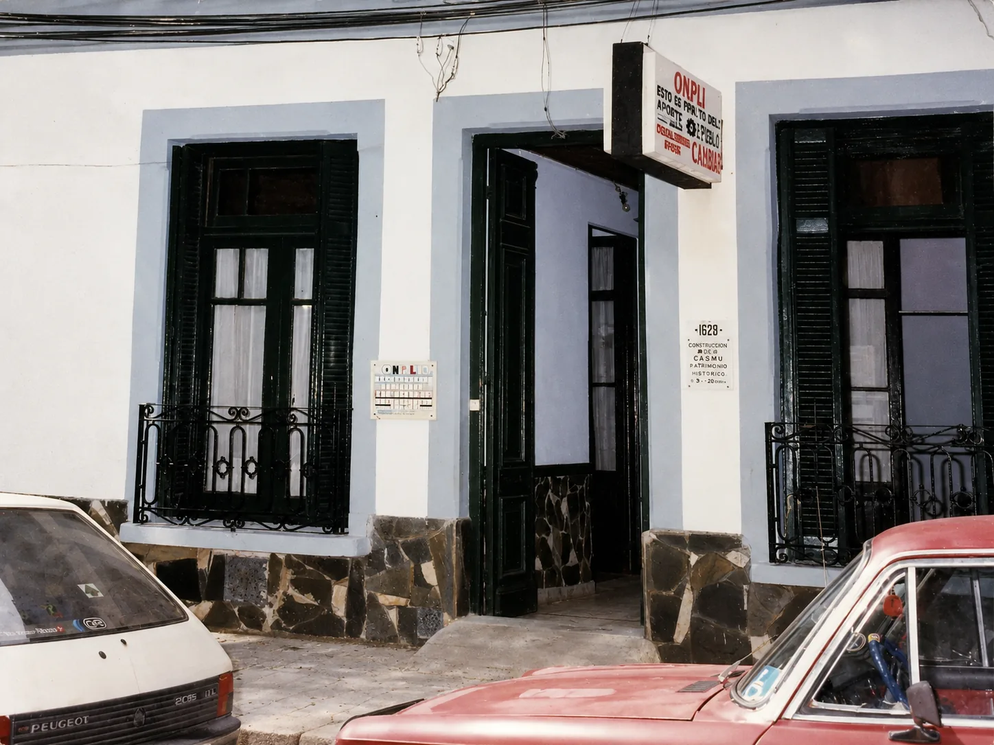 Fachada actual de la sede de ONPLI, con paredes de color y ventanas verdes.