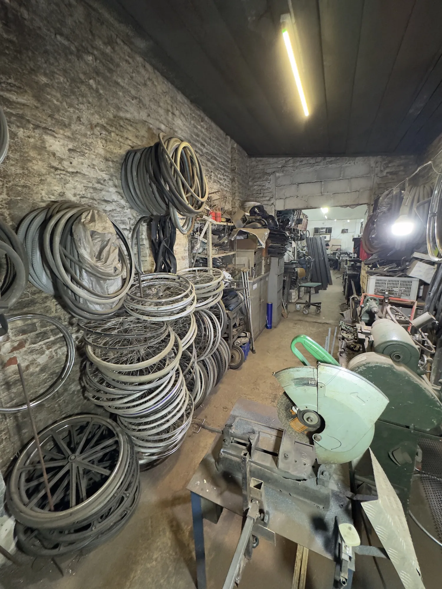 Aros y ruedas de sillas de ruedas junto a una sierra de corte en el taller metalúrgico.